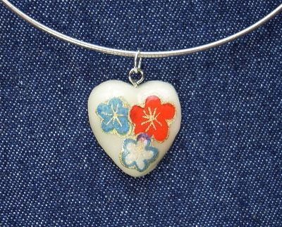 Homemade heart necklace with orange and blue flowers painted on to it.