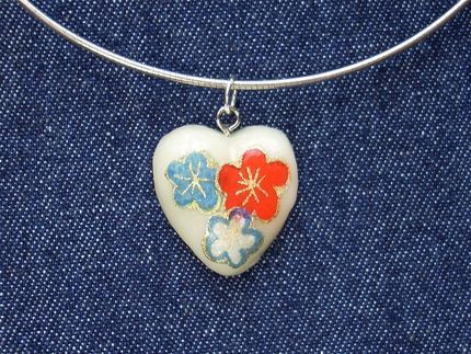 Homemade heart necklace with orange and blue flowers painted on to it.