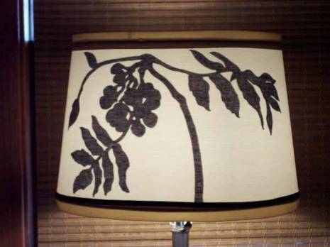 A lamp shade with a small tree that has leaves on it.