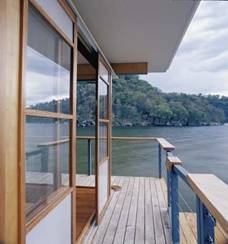 Deck of house next to lake by a forest.