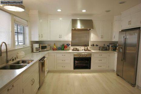 A kitchen with white cabinets and silver appliances