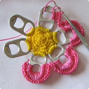 Pink thread being wrapped around can tabs.