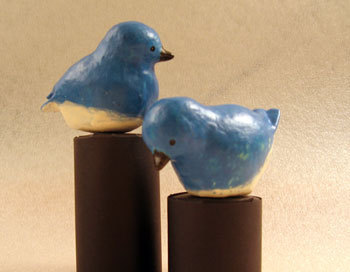 Ceramic blue birds perched on two brown pillars.