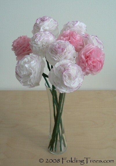 Dark pink and light pink paper carnations in a clear vase.