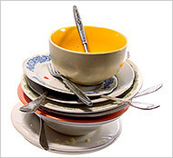Dirty dishes consisting of plates, bowls, and silverware stacked on top of each other.