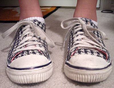 A pair of sneakers with a black pattern are tied with white shoe laces.