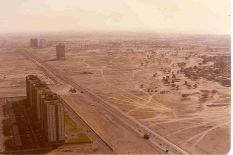 Group of skyscrapers near road and dusty field.