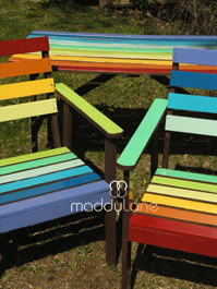 Rainbow colored wood chairs next to rainbow colored table.