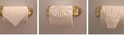 Toilet paper folded into fancy design on gold toilet paper roll holder.