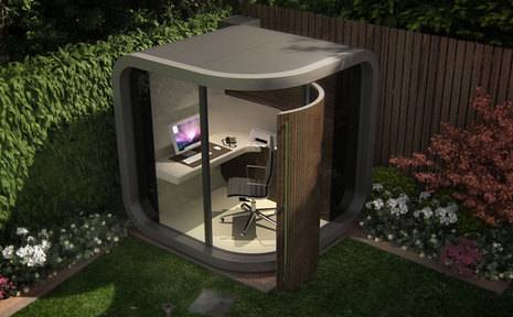 A stand alone home office is located in a corner of a backyard.