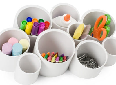 Paperclips, crayons, scissors, markers, chalk, glue are in cups designed to hold office supplies.