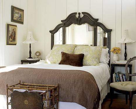 A fancy brown and white bed with mirrors on the back in a bedroom.