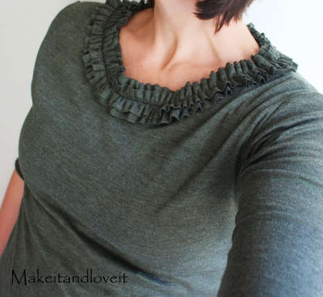 Woman showing gray color ruffly top tee neck.