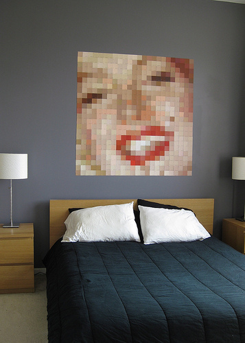 A bed room that has a blurred photo of a woman on it.