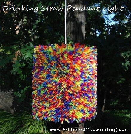 Multicolored pendant light made with drinking straws hanging to a tree in the garden.
