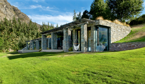 A stone house built into a hill, with glass windows.