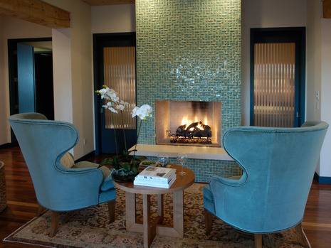 A fireplace with two blue chairs in front.