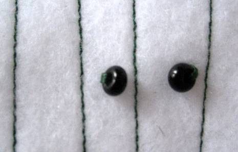 Two small black beads sewn onto felt fabric.