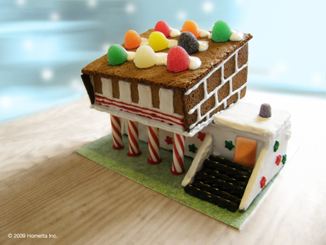 A gingerbread candy house sits on a wooden table.
