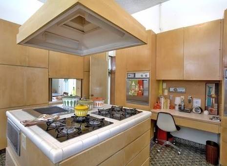 A modern kitchen made of wood with a stove in the middle.