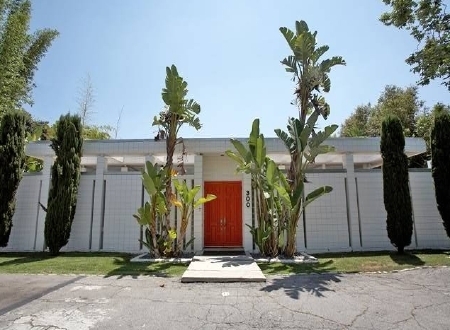 The front of a tropical, modern house with large orange doors.