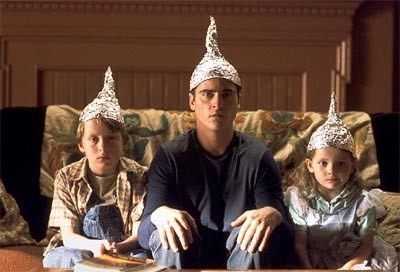 Three people sitting on a couch with tin foil hats on.