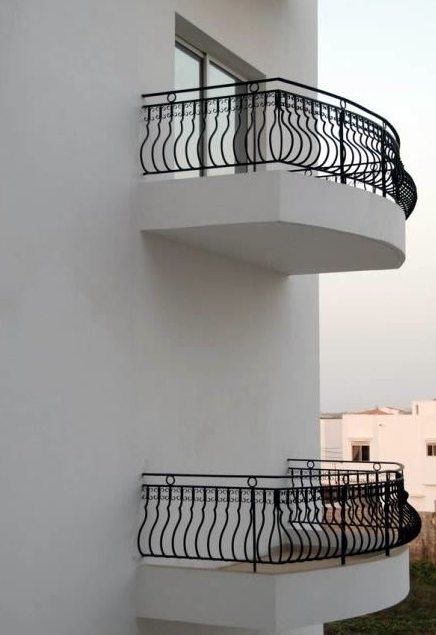 Two black balconies are along a white building..