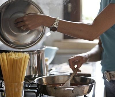 Woman cooking food in the kitchen in stainless steel utensils.