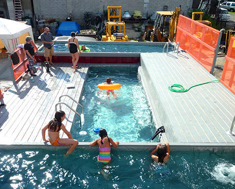 A pool with a children playing and adults standing around