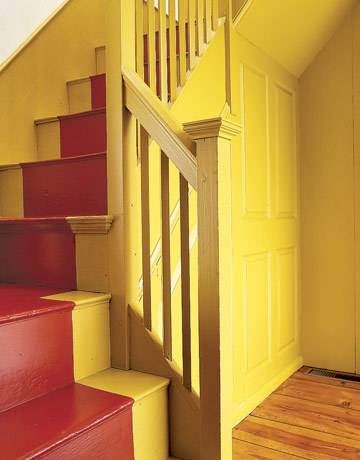 A yellow staircase space has red painted steps.