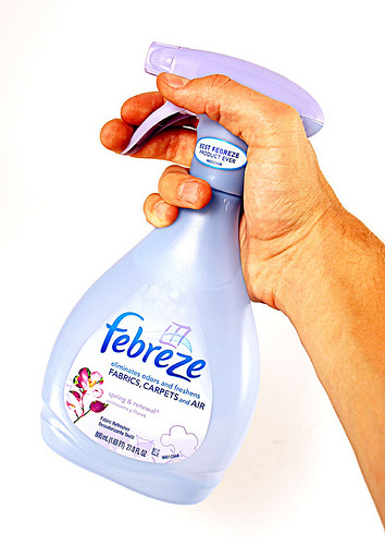 A hand is holding a squirt bottle of Febreeze.