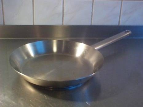 Silver metallic pan sitting on top of a table with a metal counter.