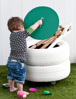 A toddler is playing with a green frisbee over Wyatt tires.