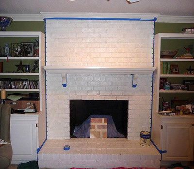 A fireplace with painted white bricks and a white mantel.