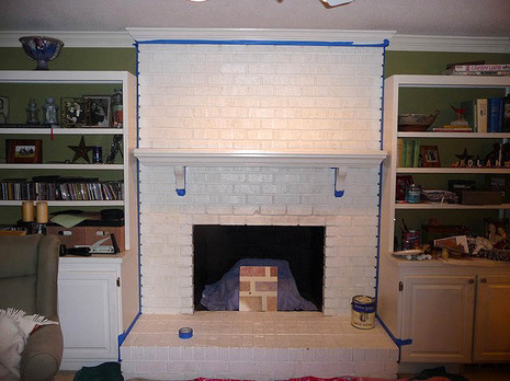 A fireplace with painted white bricks and a white mantel.