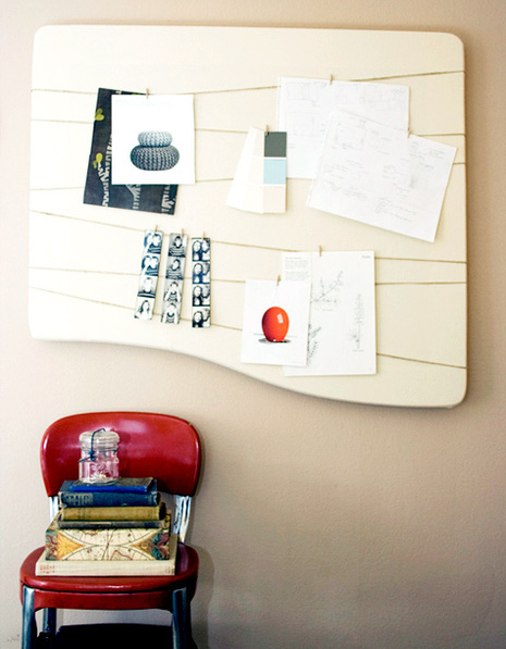 Papers are stuck on a board above a red school chair with book stacked on it.