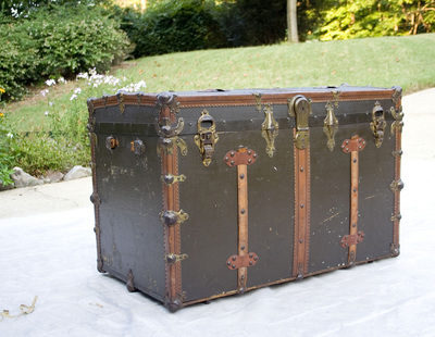 An antique brown trunk on a driveway.