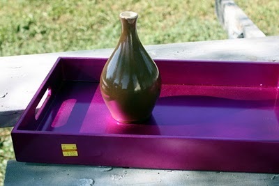 A small green vase inside of a purple plastic container.