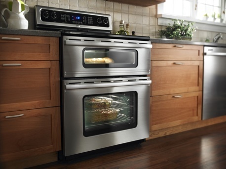 Stainless steel  double oven surrounded by wooden kitchen cabinets.
