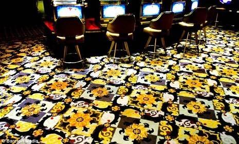 Yellow flowers and white and yellow shapes fill the black space on a casino carpet