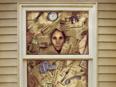 A woman standing at a window with newspapers and items around her