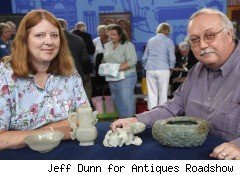 A man and a woman are showing off the antique objects that they have collected.