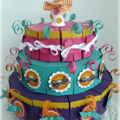 A three layer round shape cake decorated with many colorful ribbons.