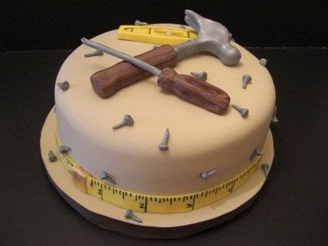 A cake with a hammer a screwdriver and loose nails as frosting.
