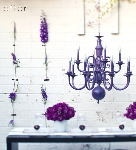 A purple chandelier hangs near purple decor on a white wall.