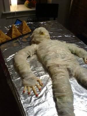 a meat loaf which resembles a mummy placed on a foil paper.