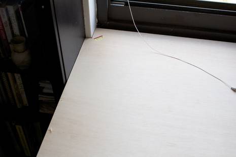 Some books are arranging in the cupboard which is near the white table.