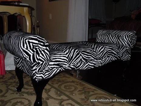 A scroll arm bench has a black and white zebra print upholstery with black legs.