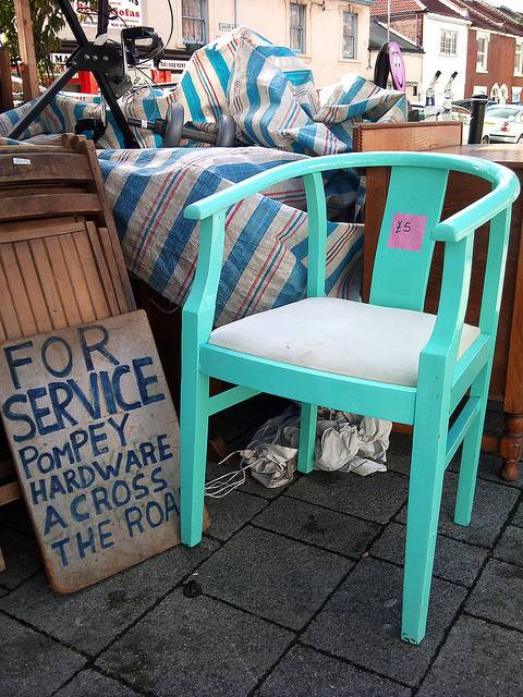 A sea castle green chair at the foot of a bed.