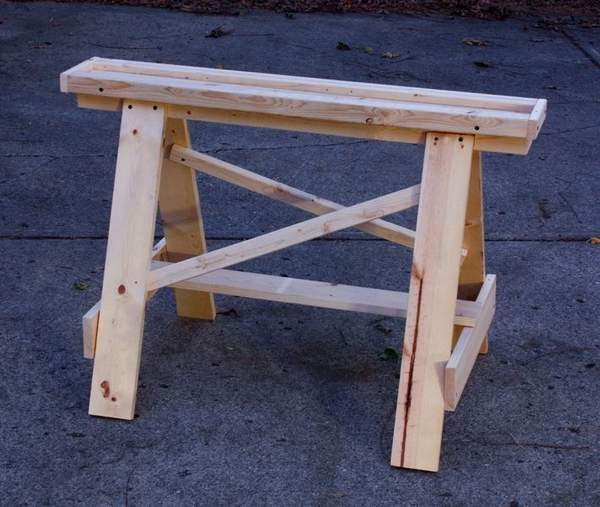 An unvarnished wooden sawhorse is on a blue floor